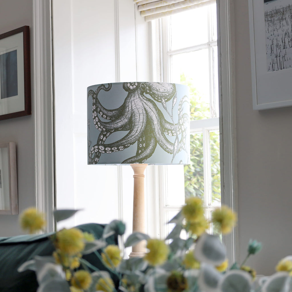 Decorative lamp with a patterned shade in a room with a window and framed pictures.