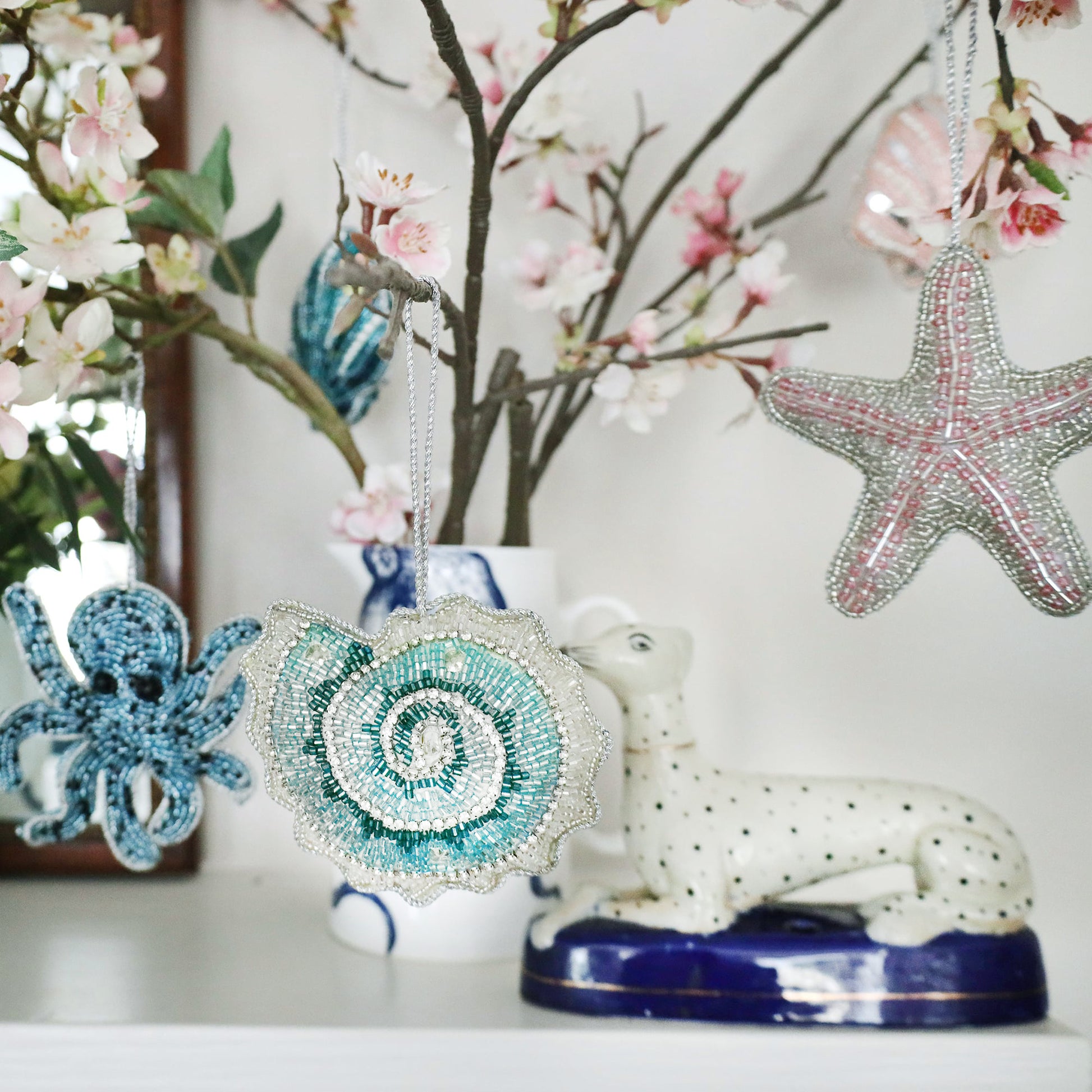 Decorative ornaments including a starfish, octopus, and shell on a stand with floral background