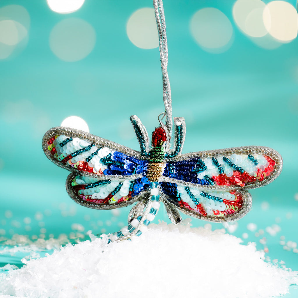 Decorative dragonfly ornament with colorful patterns on a snowy surface and blurred light background
