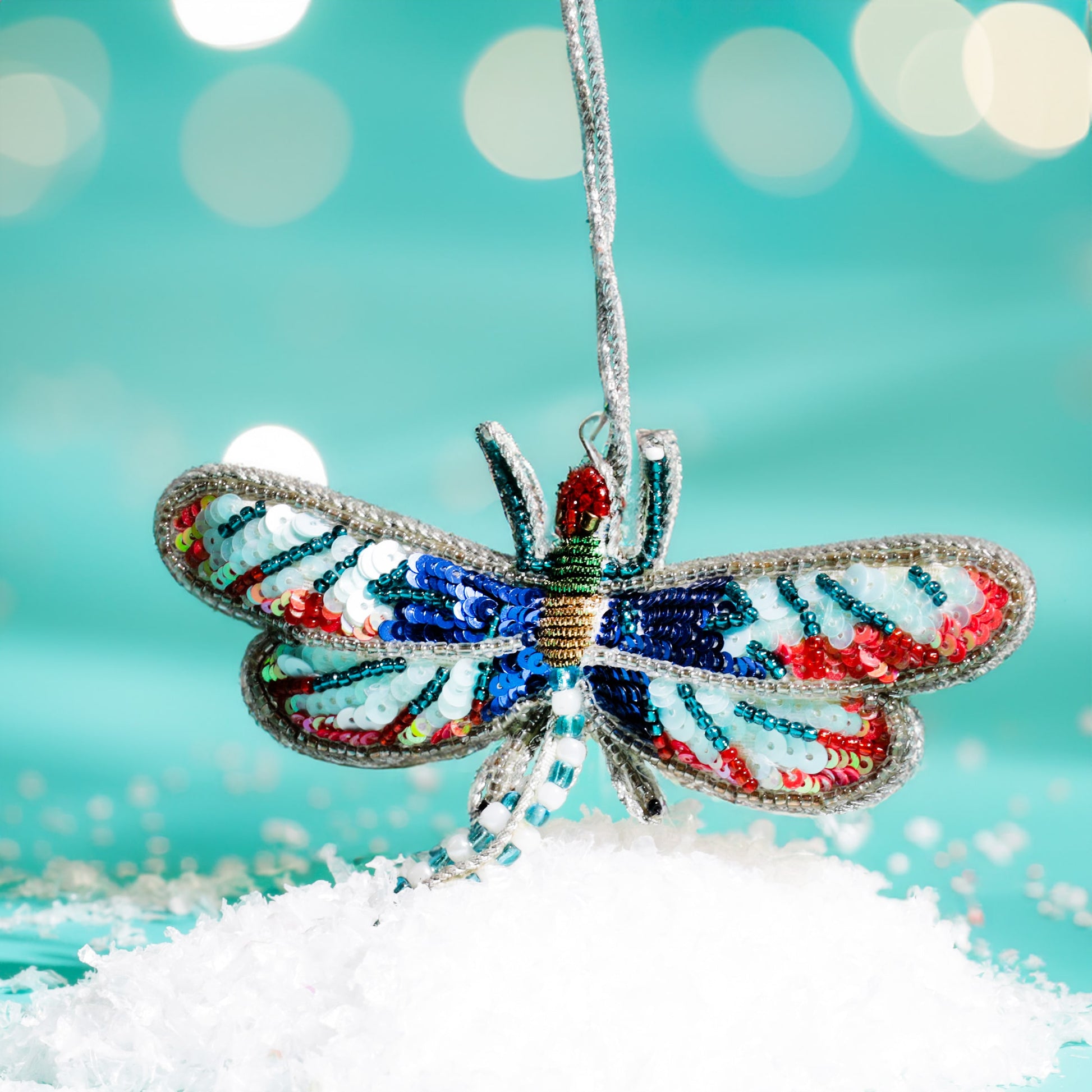 Decorative dragonfly ornament with colorful patterns on a snowy surface and blurred light background