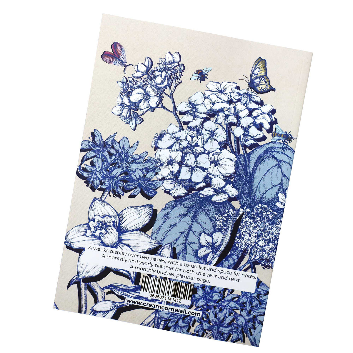 Cream-coloured diary back cover featuring blue and white floral illustrations, including hydrangeas, daffodils, and butterflies, with a white text strip at the bottom containing a barcode and website.