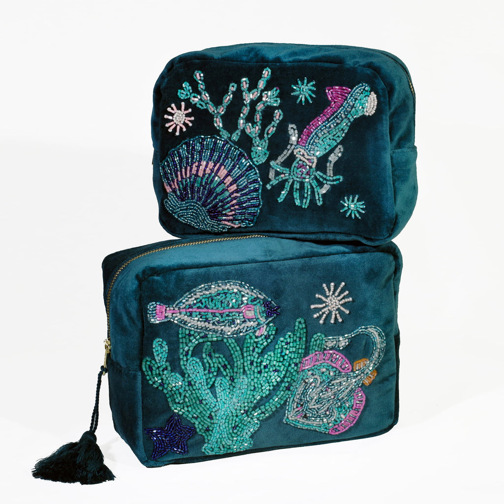 Two teal makeup bags with ocean-themed beading on a white background