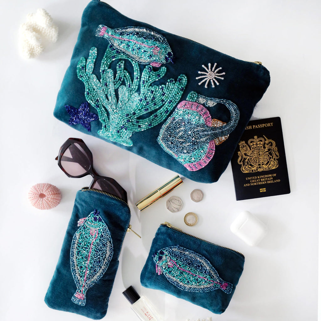 Set of three embroidered pouches with marine designs on a white surface.