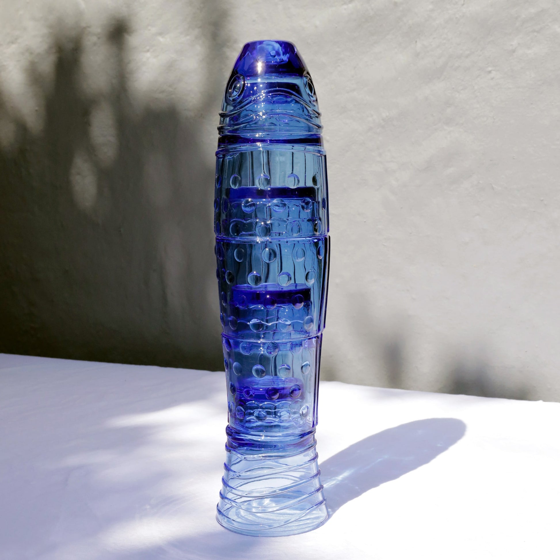 Blue cylindrical fish stack glasses with textured surface on a light background