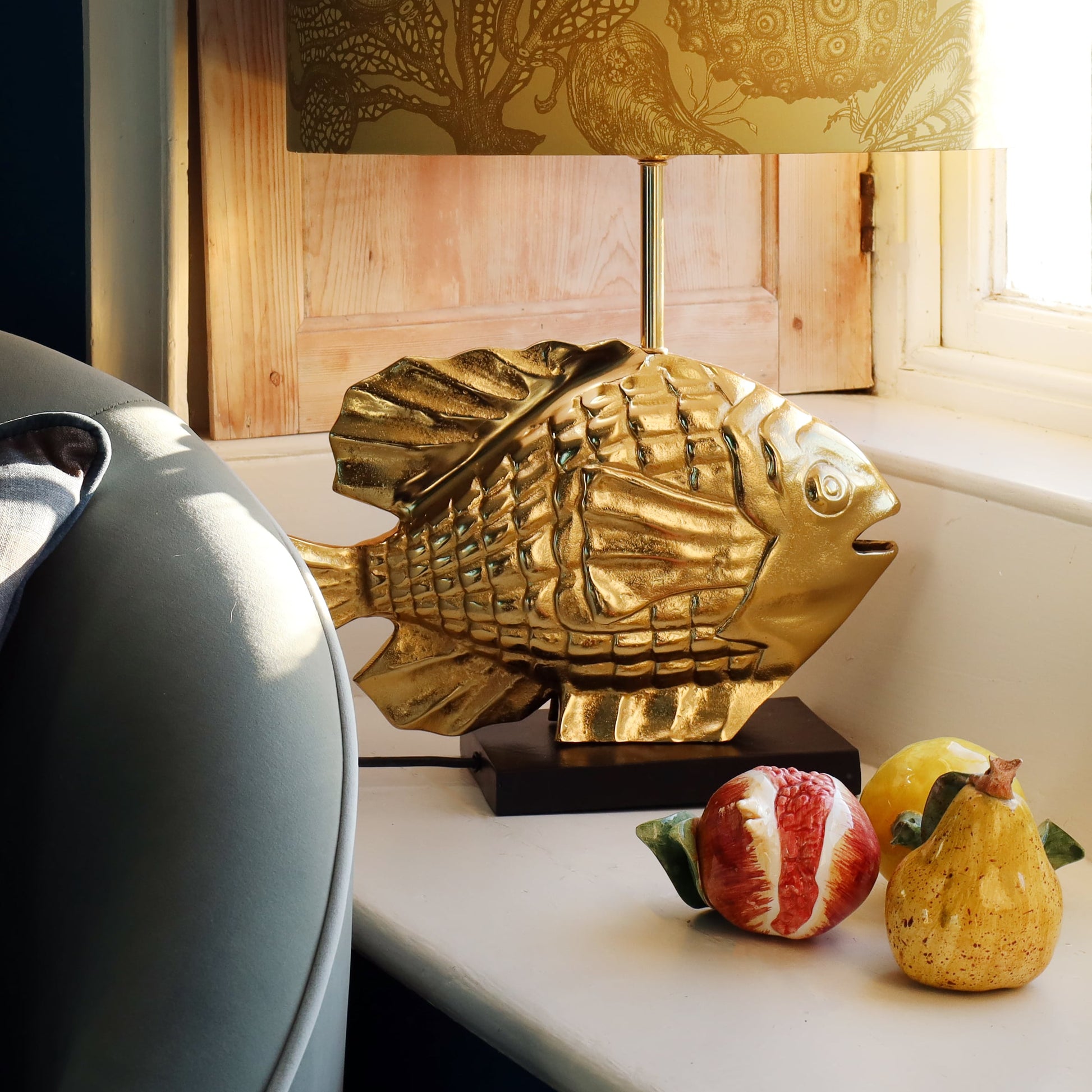 Gold fish-shaped lamp on a surface with decorative items in the background