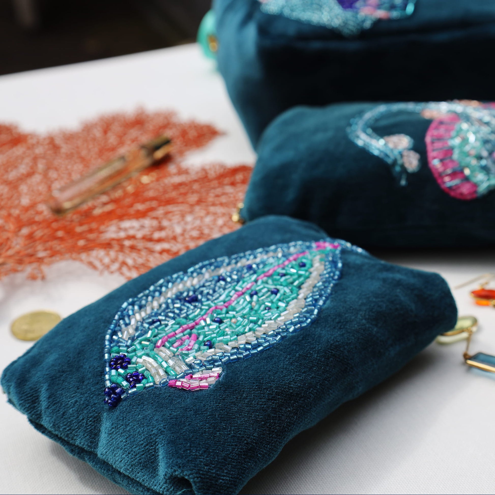 Blue embroidered pouches with colorful beadwork on a white surface.