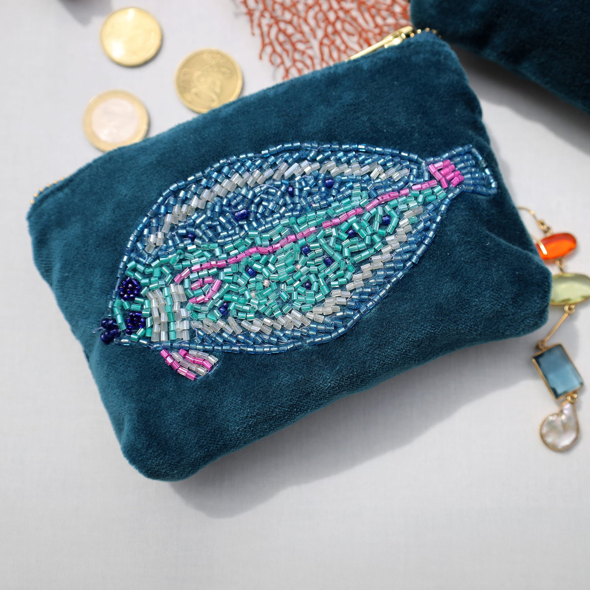 Blue embroidered pouch with a fish design on a white surface