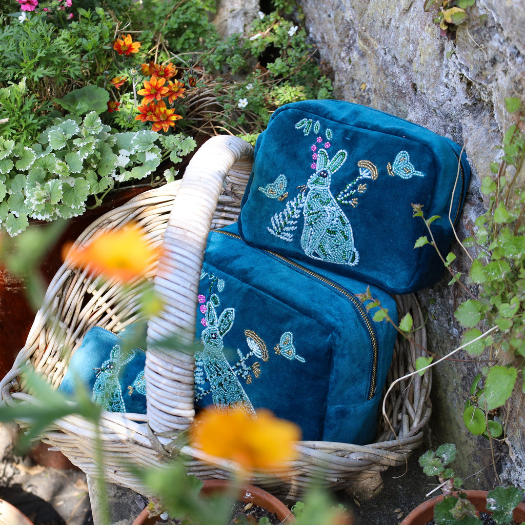 Blue embroidered bag with a rabbit design in a garden setting