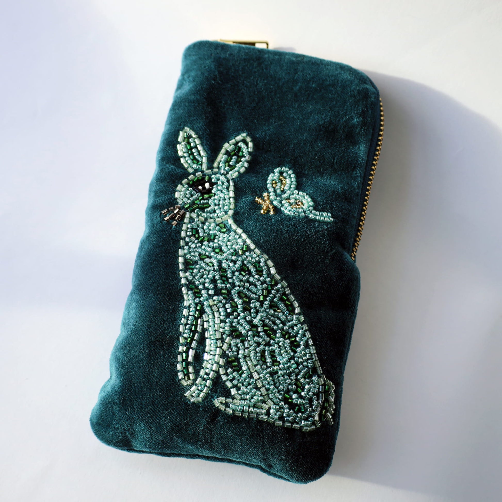 Teal velvet pouch with beaded rabbit design on a white background