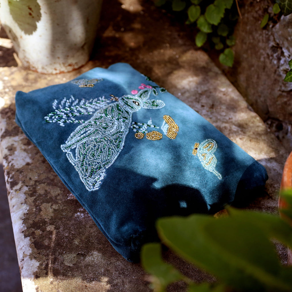 Blue embroidered pouch on a stone surface with plants in the background