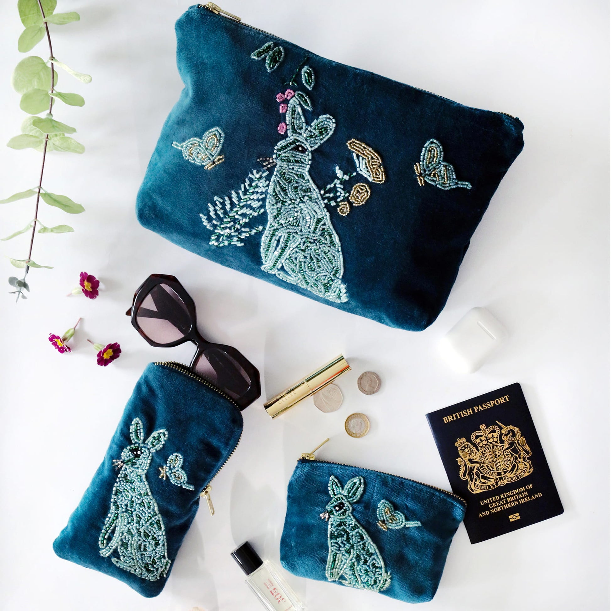 teal beaded pouches with hare design on a white surface with accessories.