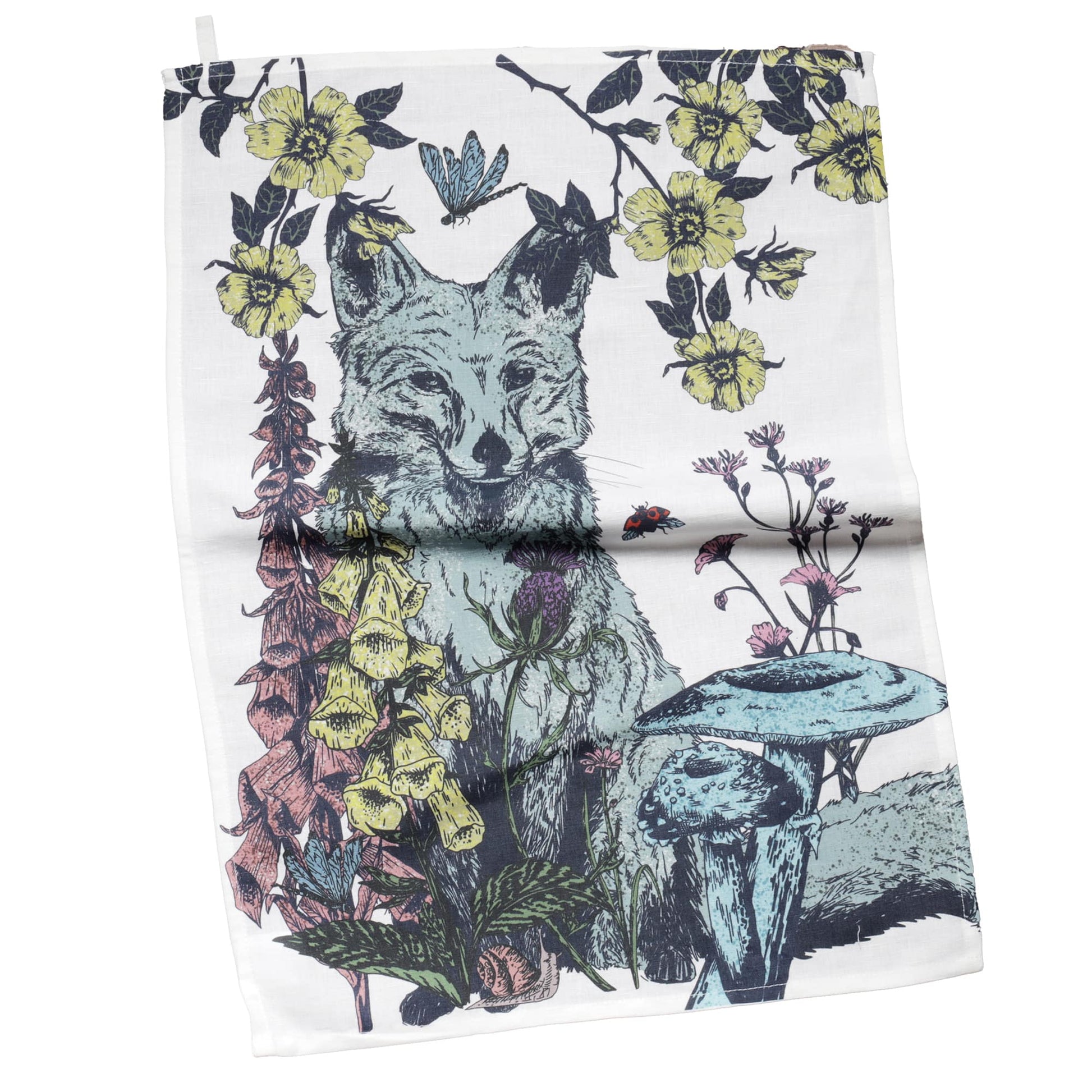 Tea towel featuring a detailed woodland illustration of a fox surrounded by foxgloves, yellow blossoms, thistles, mushrooms, and climbing vines. The design includes a butterfly and a ladybird, with a nature-inspired colour palette of green, yellow, pink, and blue on a white background.
