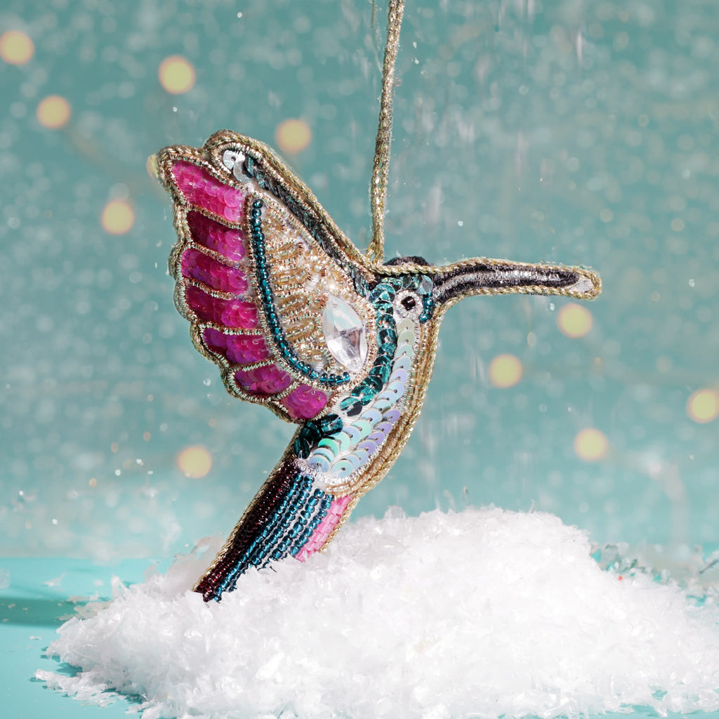 Decorative hummingbird ornament with sequins on a snowy surface