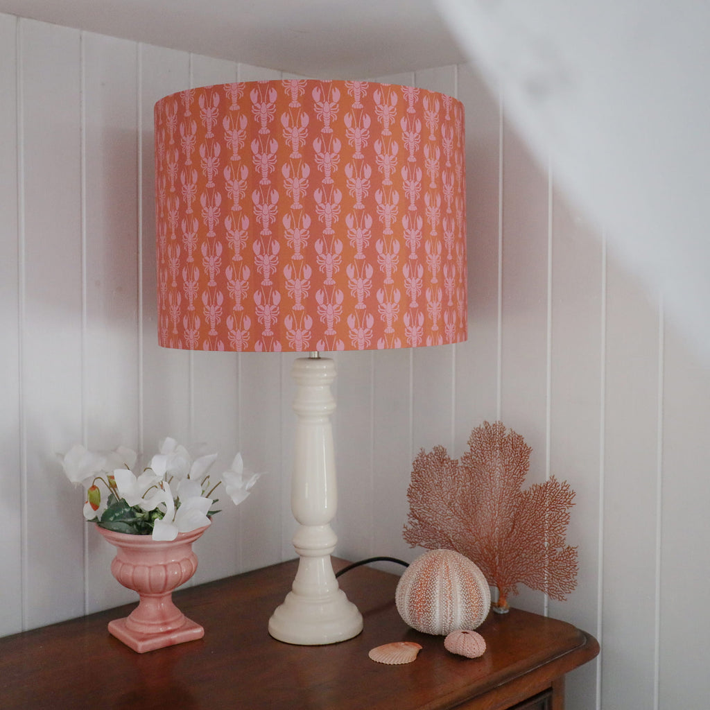 Lamp with a patterned orange shade on a wooden surface with decorative items.