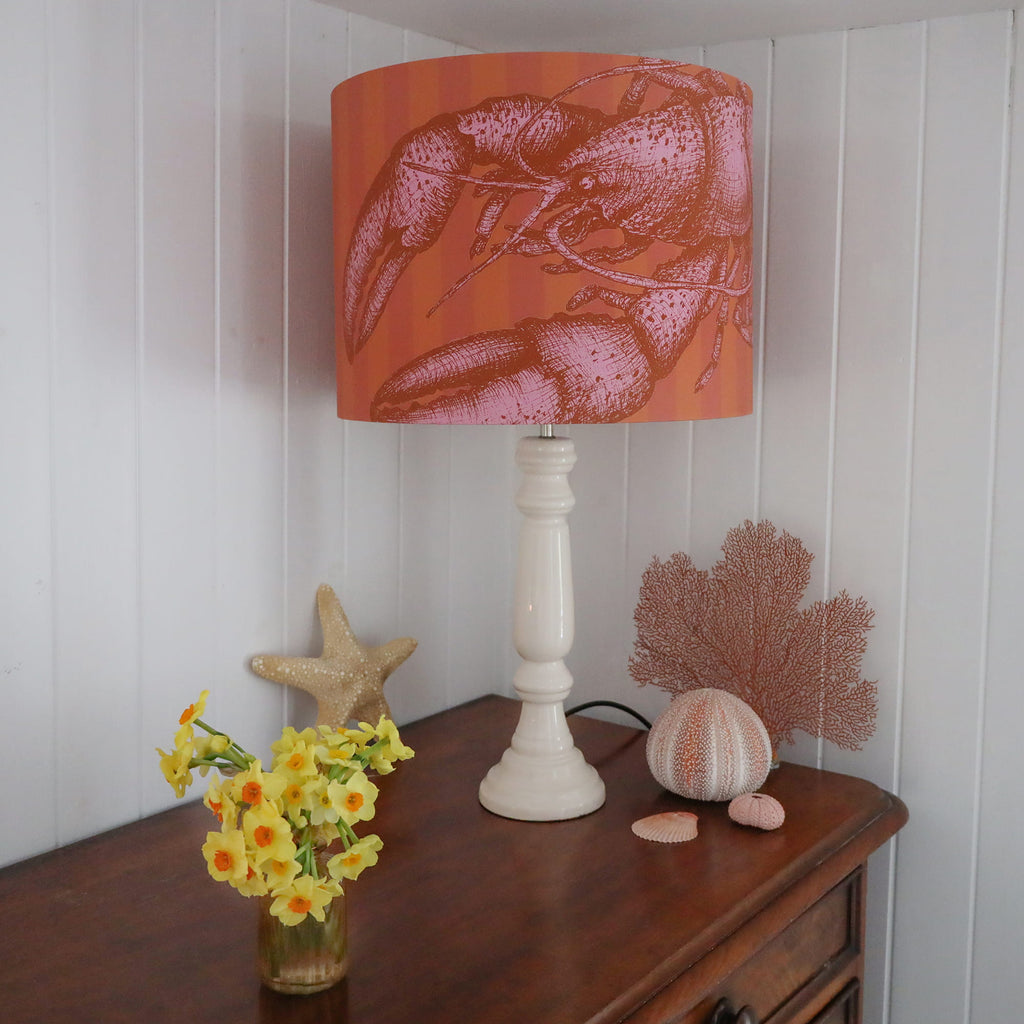 Lamp with a lobster-patterned shade on a wooden surface with decorative items.