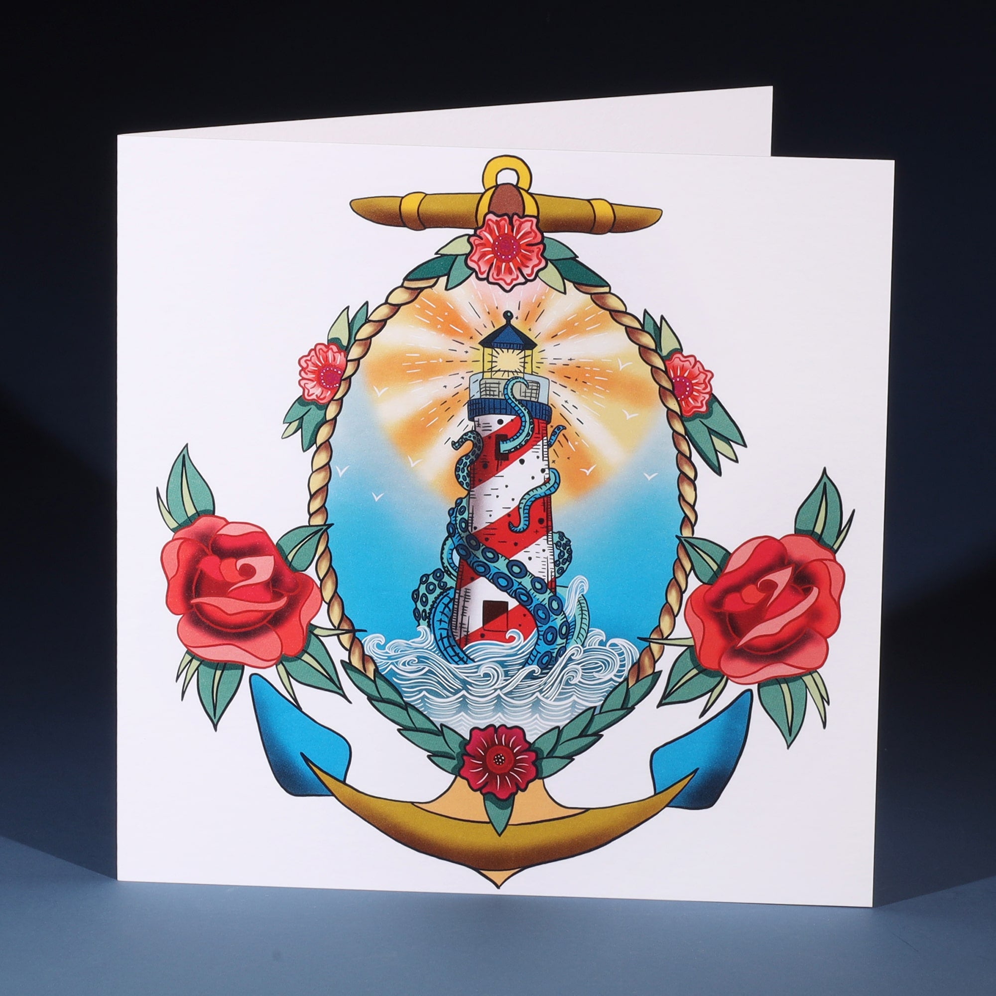 White greeting card n with a tattoo inspired illustration of a lighthouse and kraken sitting within a rope and anchor.