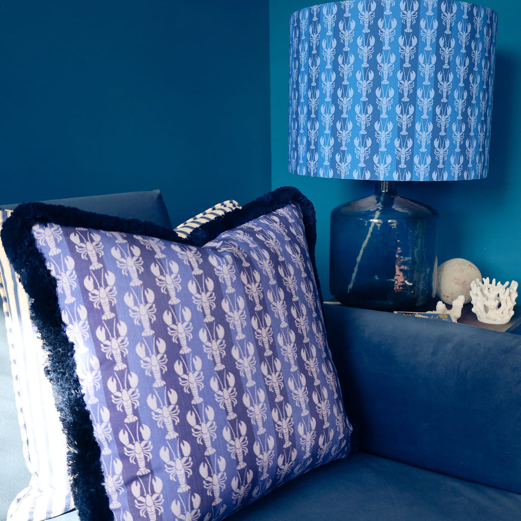 Blue pillow and lamp with lobster pattern against a blue wall