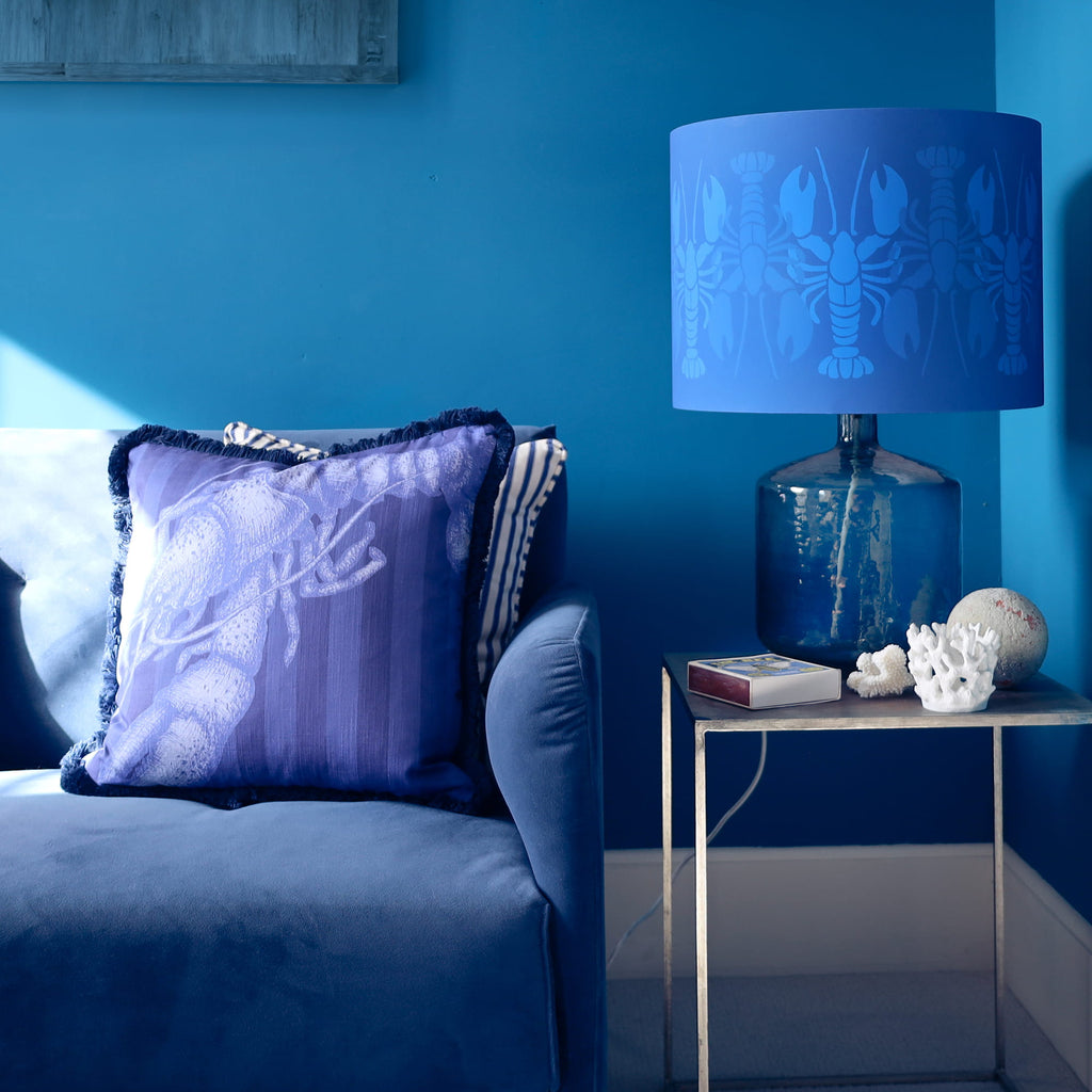 Blue-themed bedroom with a bed, lamp, and decorative items against a blue wall.