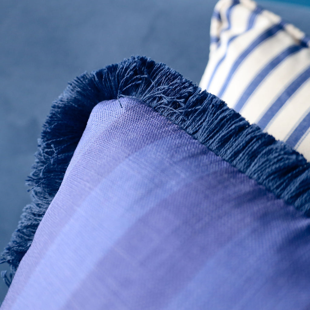 Close-up of blue fabric with frayed edge against a blurred background