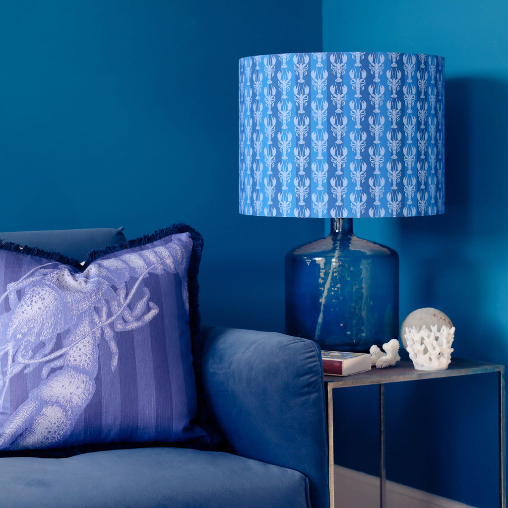 Blue lamp with mini lobster patterned shade on a side table against a blue wall
