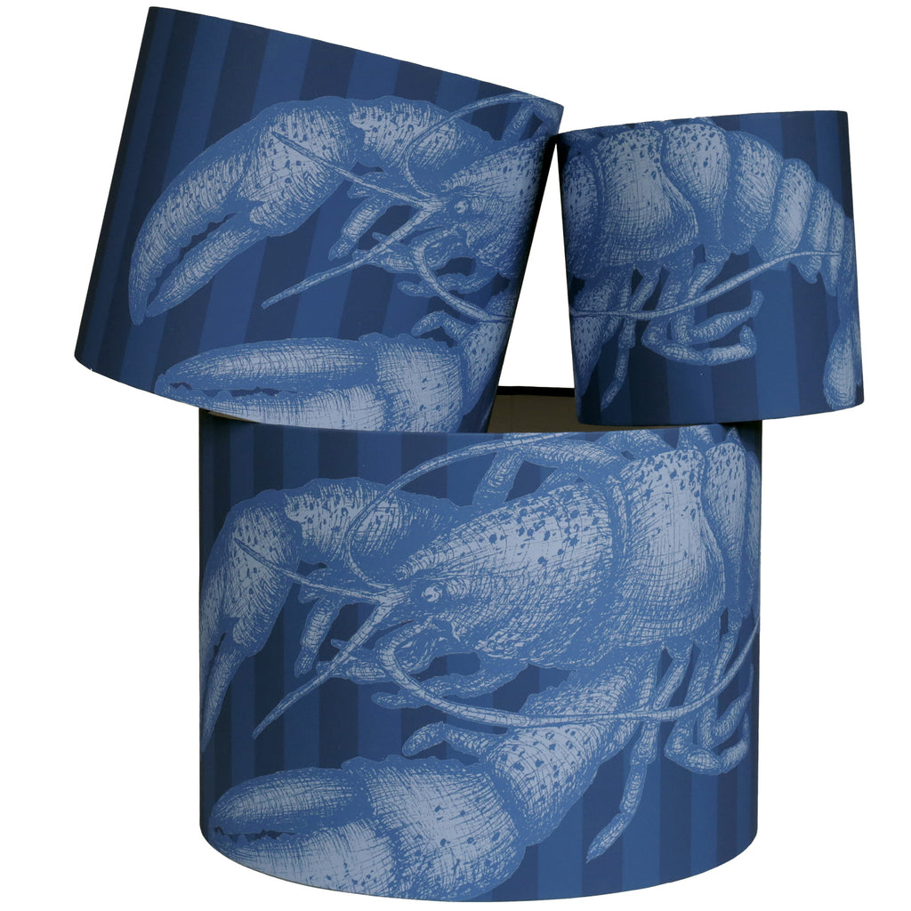 Three cylindrical lampshades with blue lobster pattern on a white background