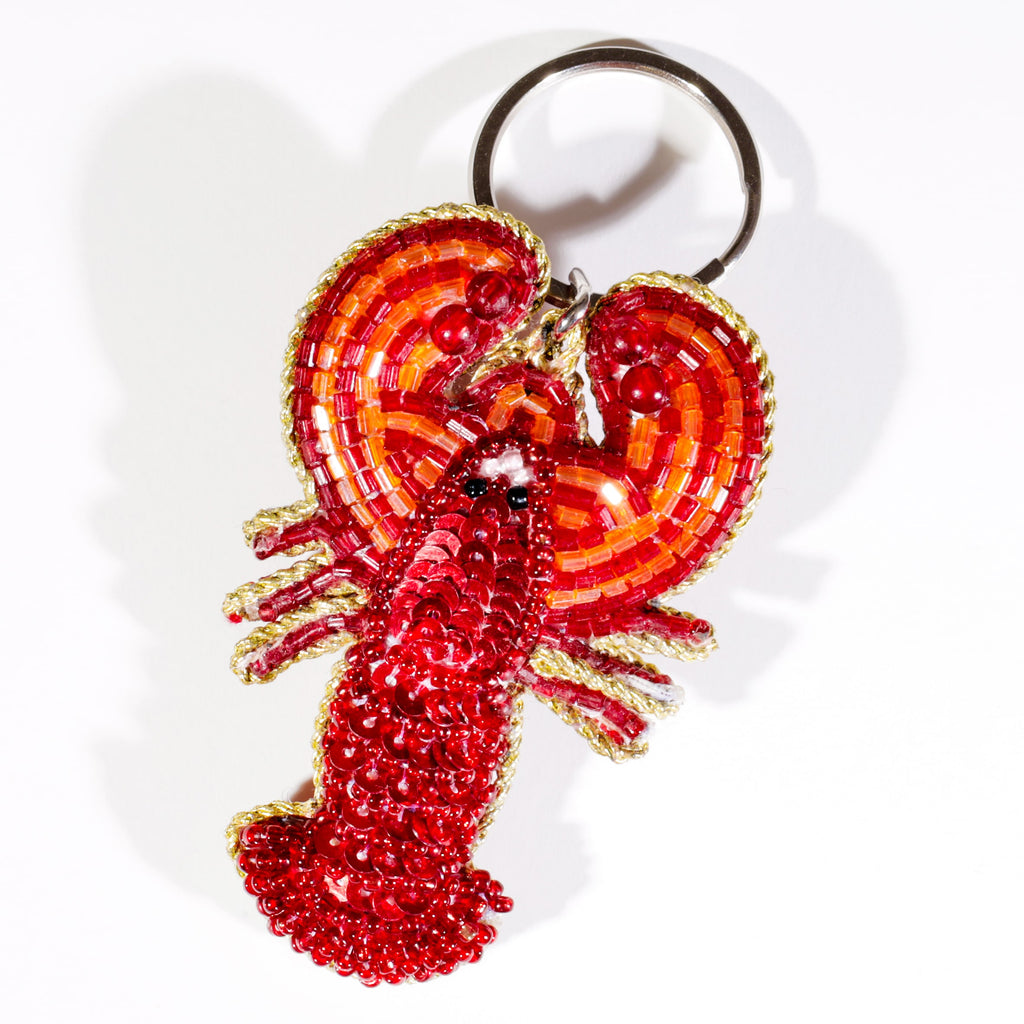 A beaded lobster keyring decorated with vibrant red and orange beads and black bead eyes, displayed against a white background.