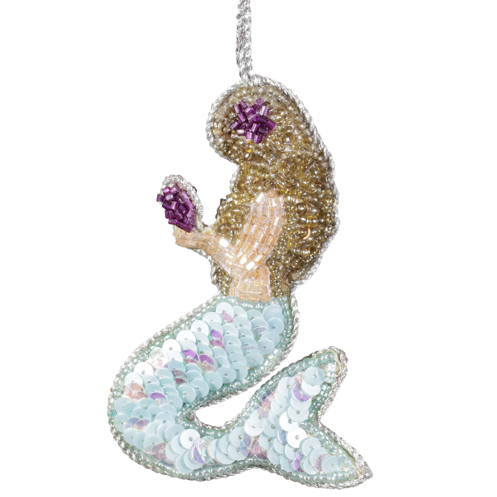 A beaded mermaid decoration with a shimmering turquoise tail, golden hair, and purple accents, holding a small purple shell, hanging by a silver thread.