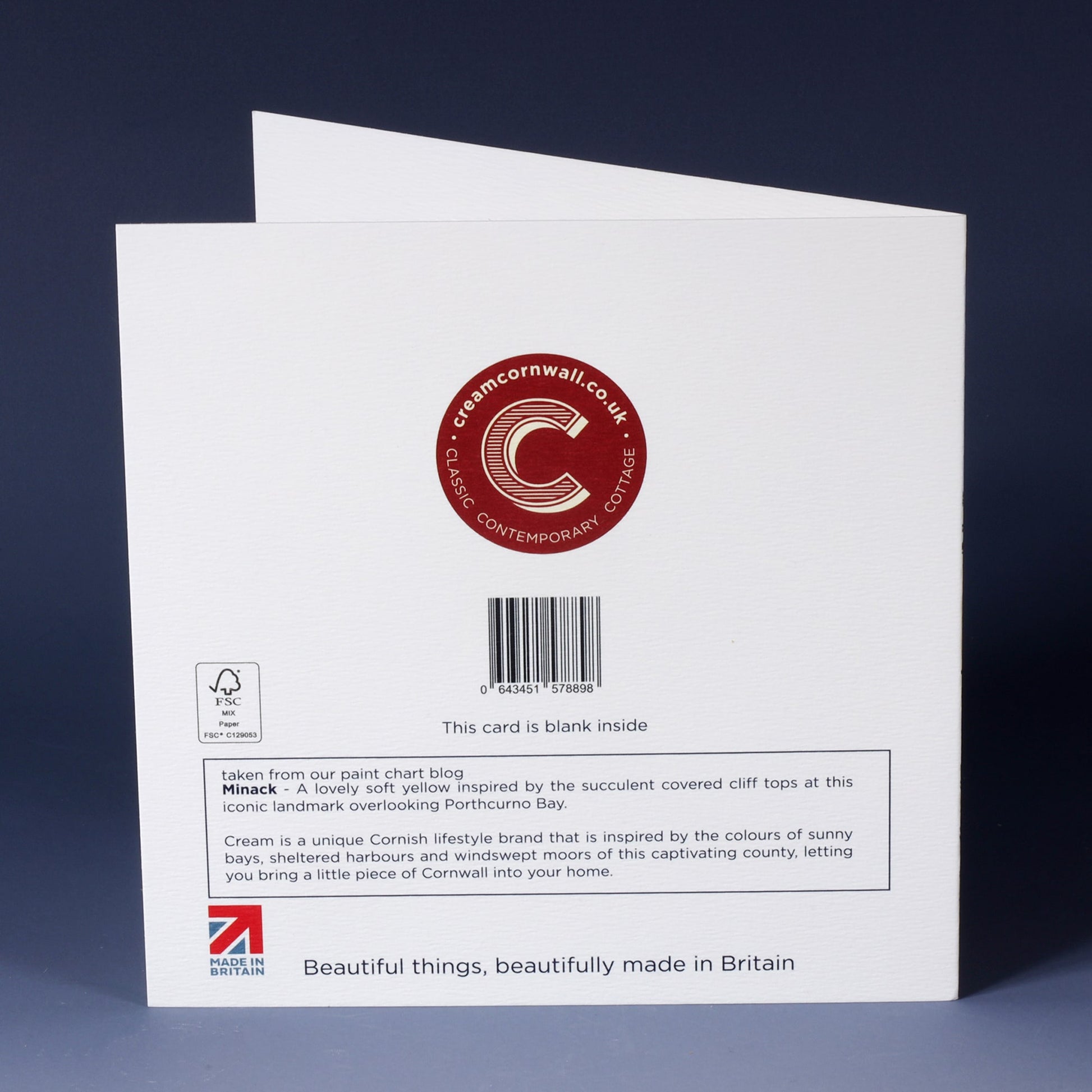 back of white greeting card with barcode, description and red cream cornwall logo standing on an ombre blue background