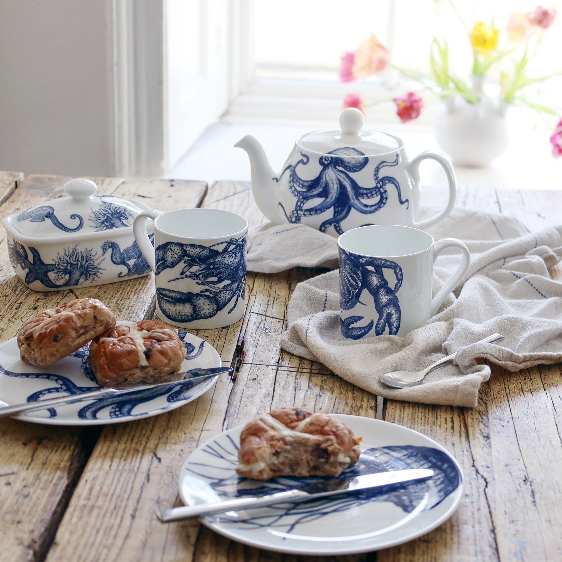 Tea set with blue and white octopus design on a wooden table with pastries.