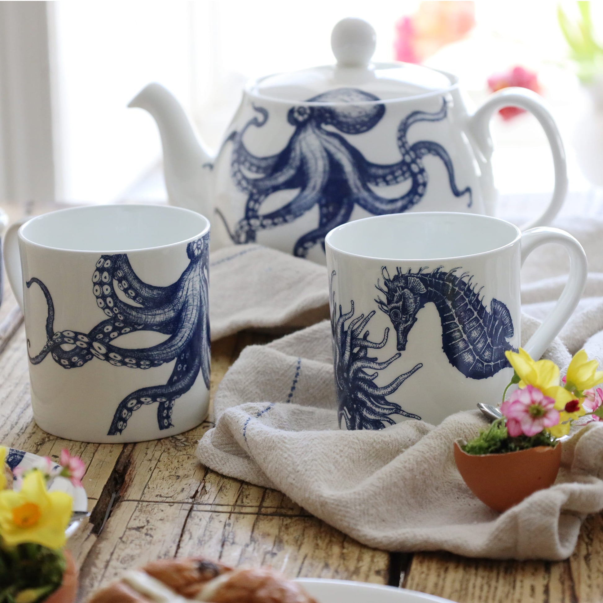 Tea set with blue octopus and seahorse designs on white mugs and a teapot.