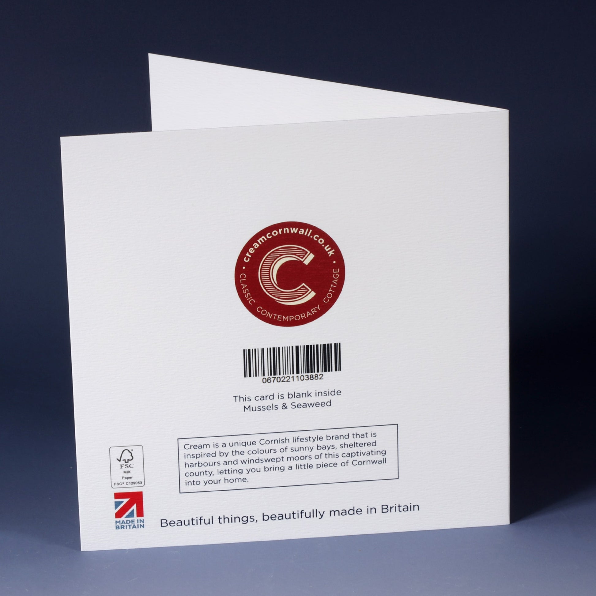back of white greeting card, with barcode, description and cream cornwall logo in red standing on an ombre blue background