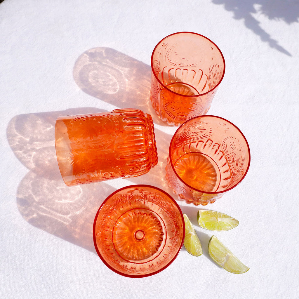 Set of red glass tumblers on a white surface with lime wedges.