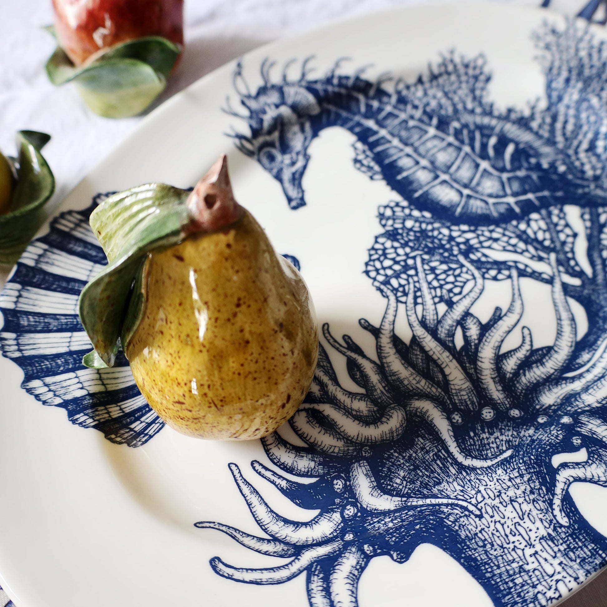 Pear on a decorative plate with blue and white sea-themed design