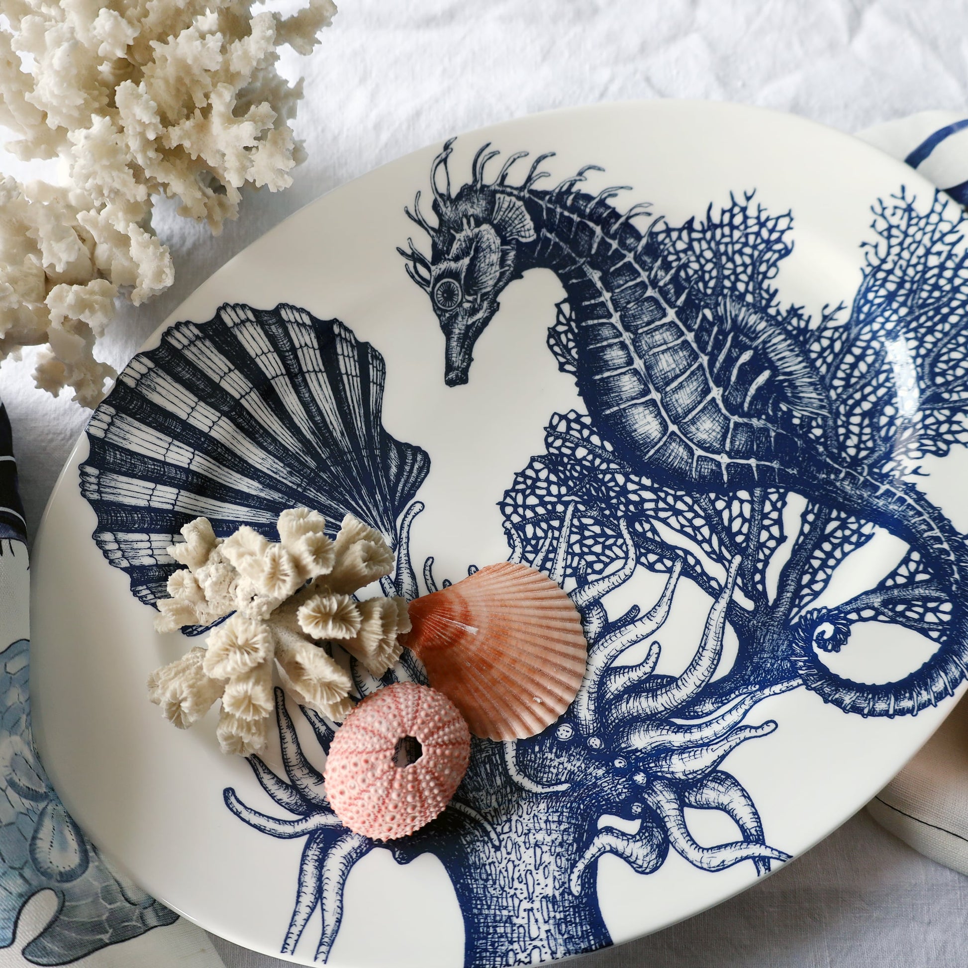 Decorative plate with blue seahorse design, coral, and shells on a white background