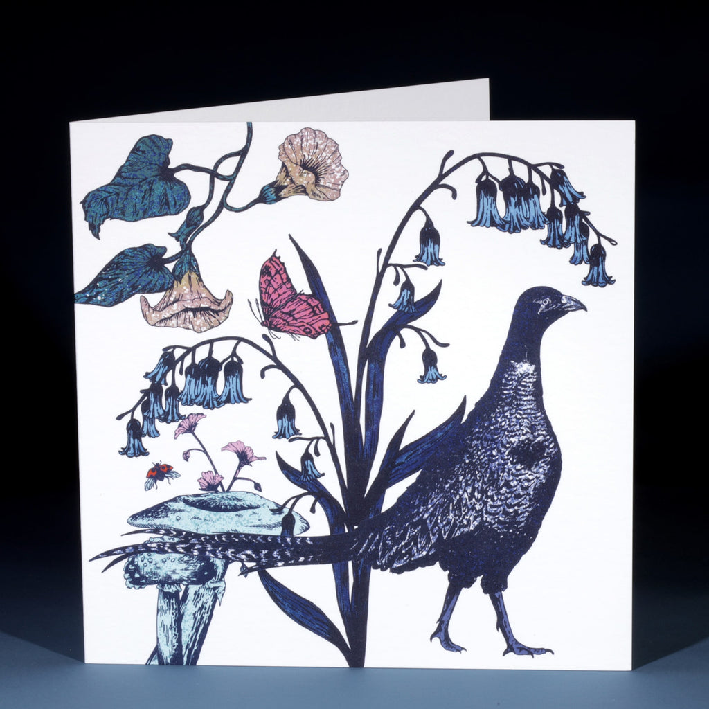 Illustrated greeting card featuring a pheasant standing among bluebell flowers, mushrooms, and wild blooms, with a pink butterfly and ladybird adding vibrant detail against a white background.
