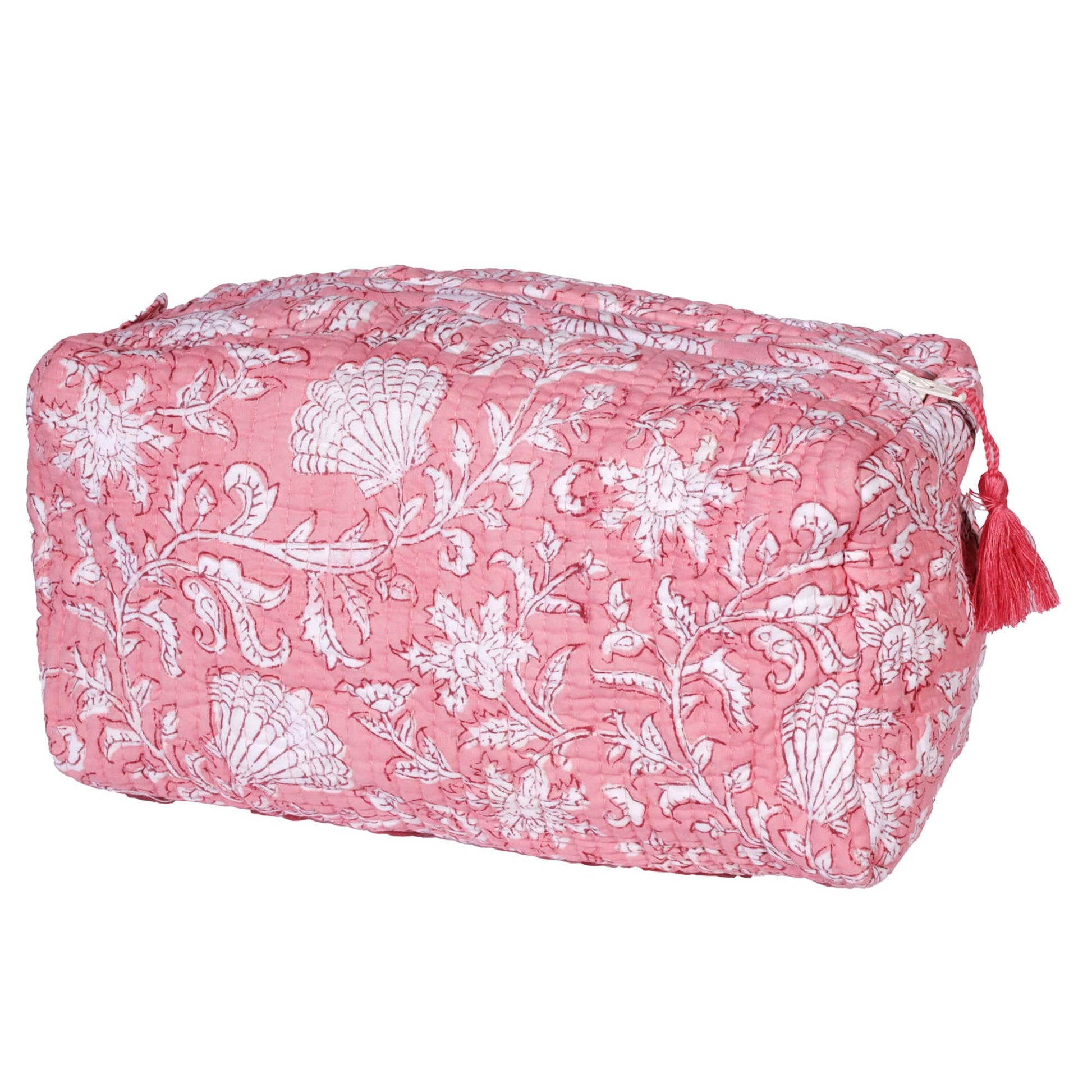 A pink quilted wash bag featuring an intricate block print design with white floral and seashell motifs, adorned with a matching pink tassel on the zipper.
