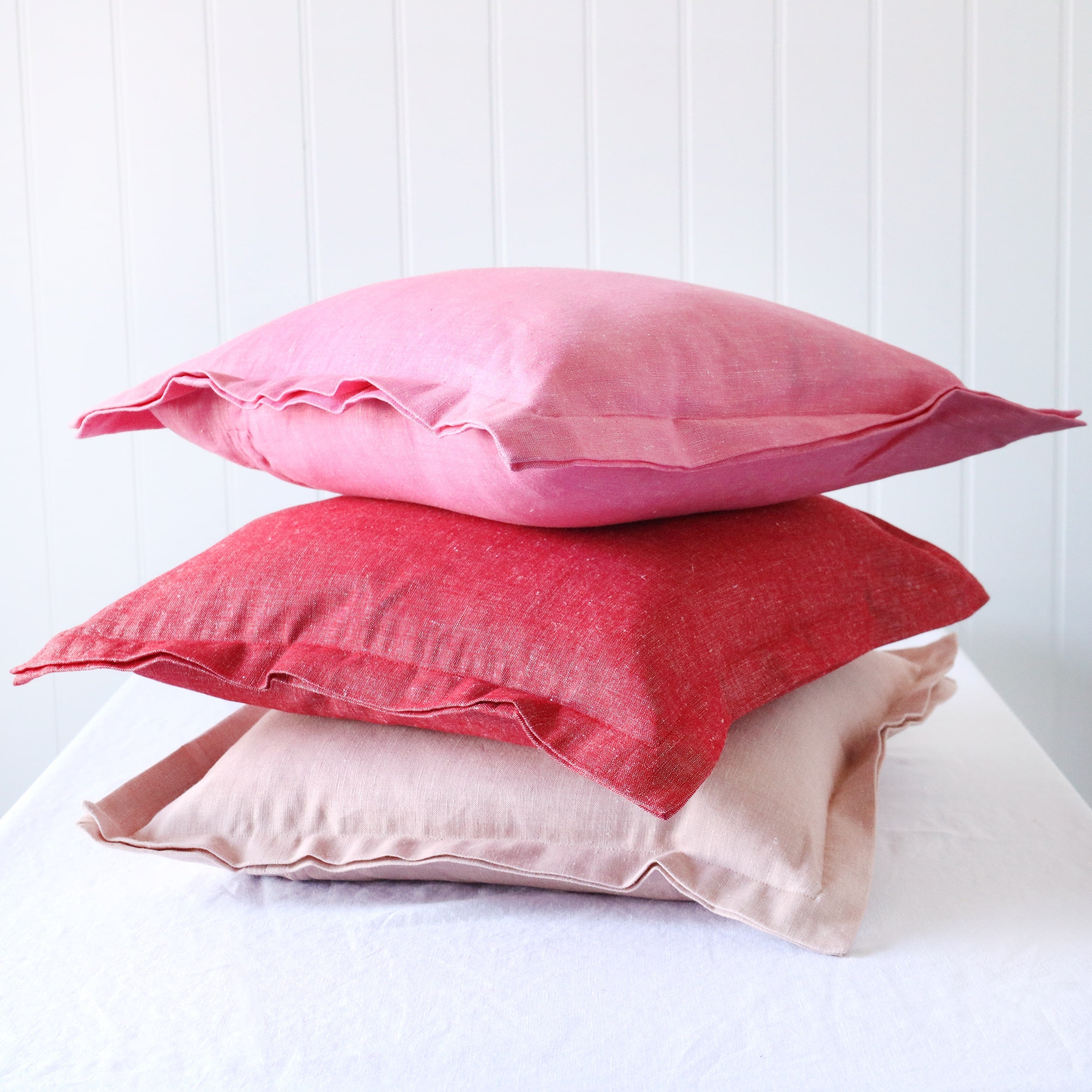 soft pink, red and hot pink chambray cushions with double flange in a pile on white background