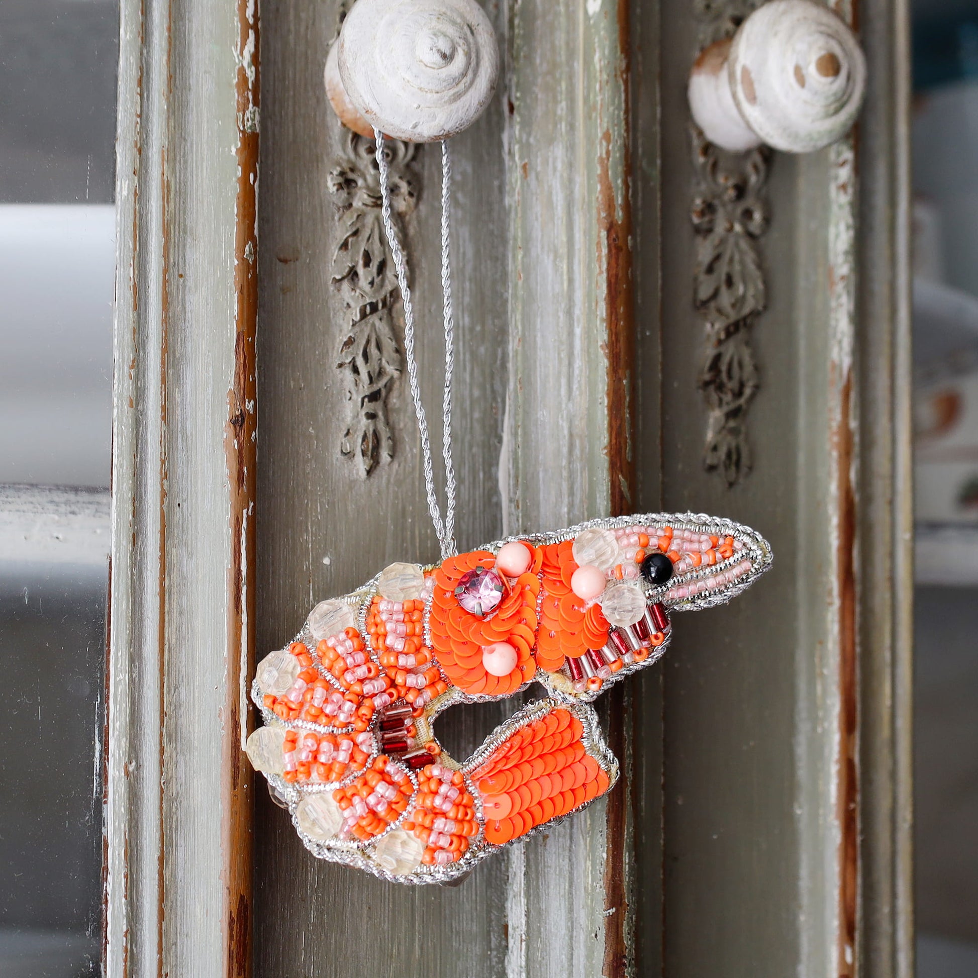 Decorative orange and white fish ornament hanging on a textured wall.