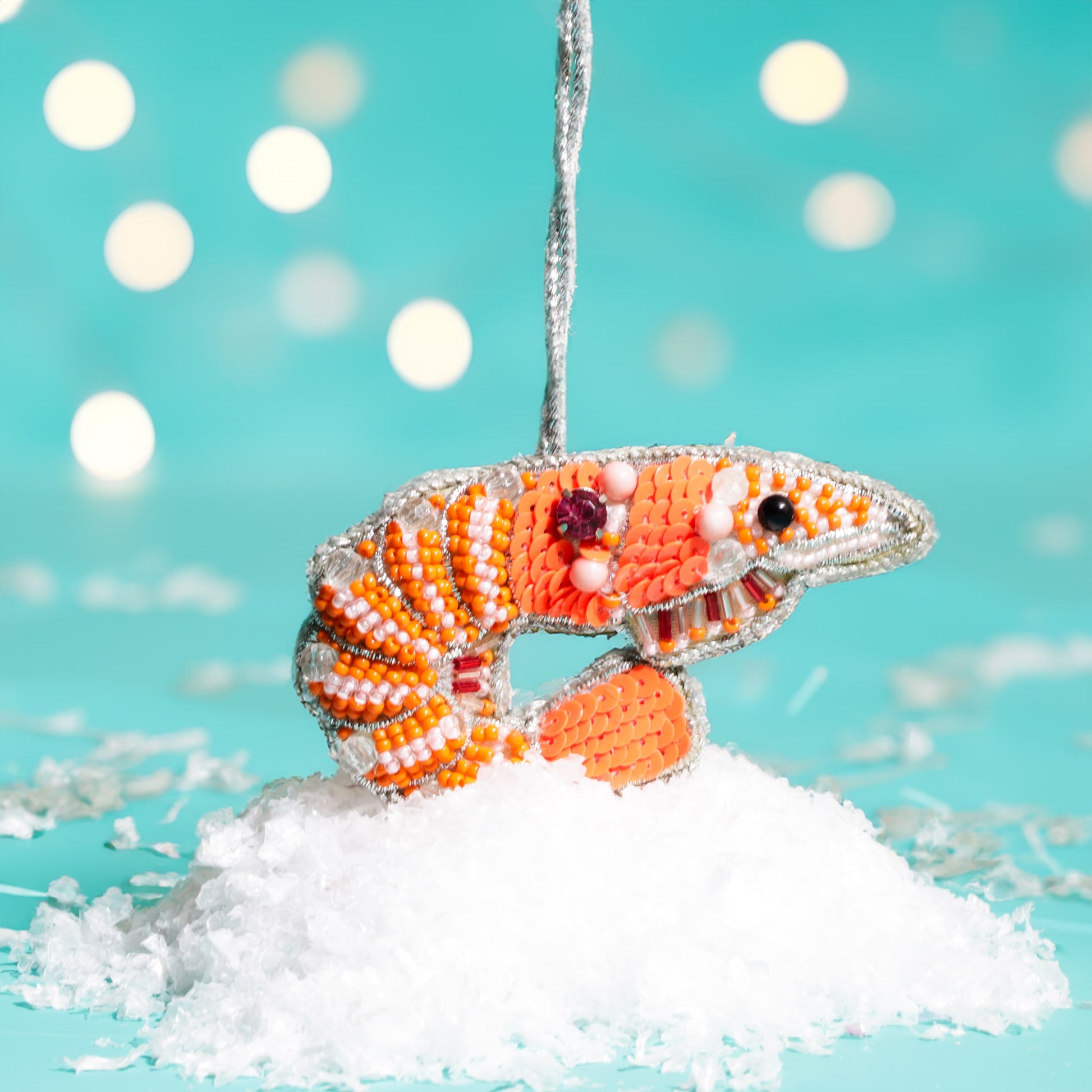Decorative shrimp ornament on a snowy branch with a blue background