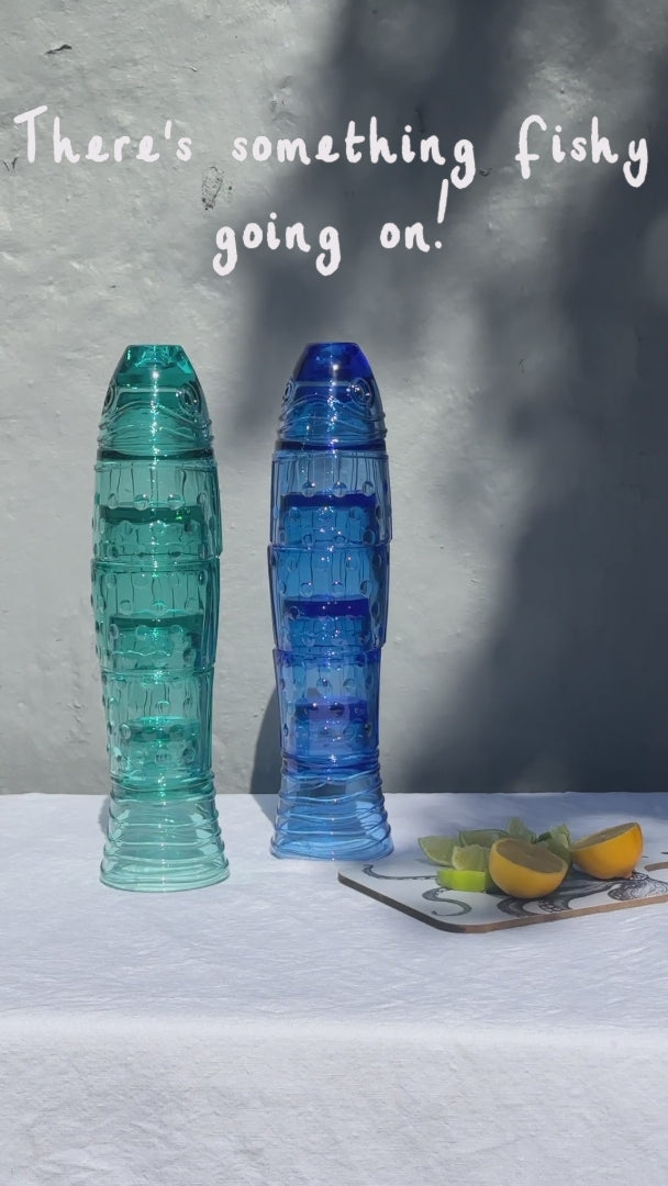 Movie with 2 stacking fish glass sets in turquoise & blue. Stacking fish glasses forming the shape of a fish, displayed on a white surface with sunlight and shadow.
