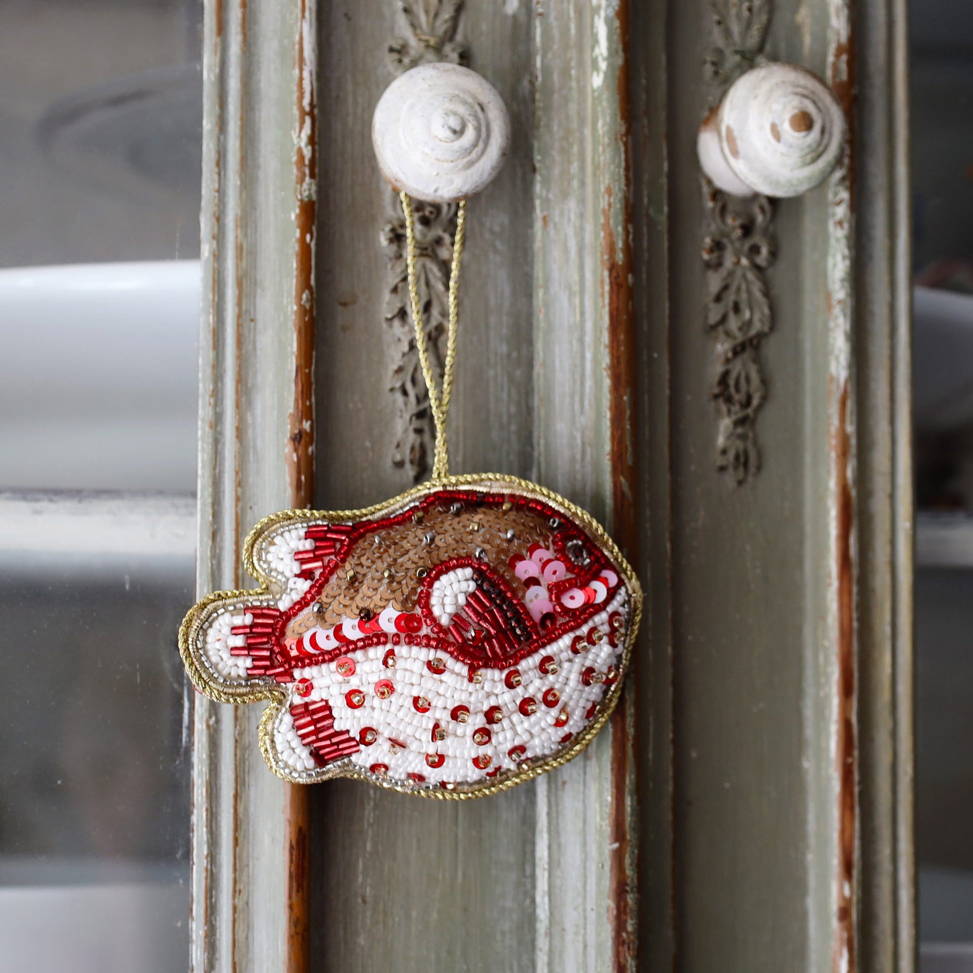 Decorative fish ornament with red and white patterns hanging on a textured wall.