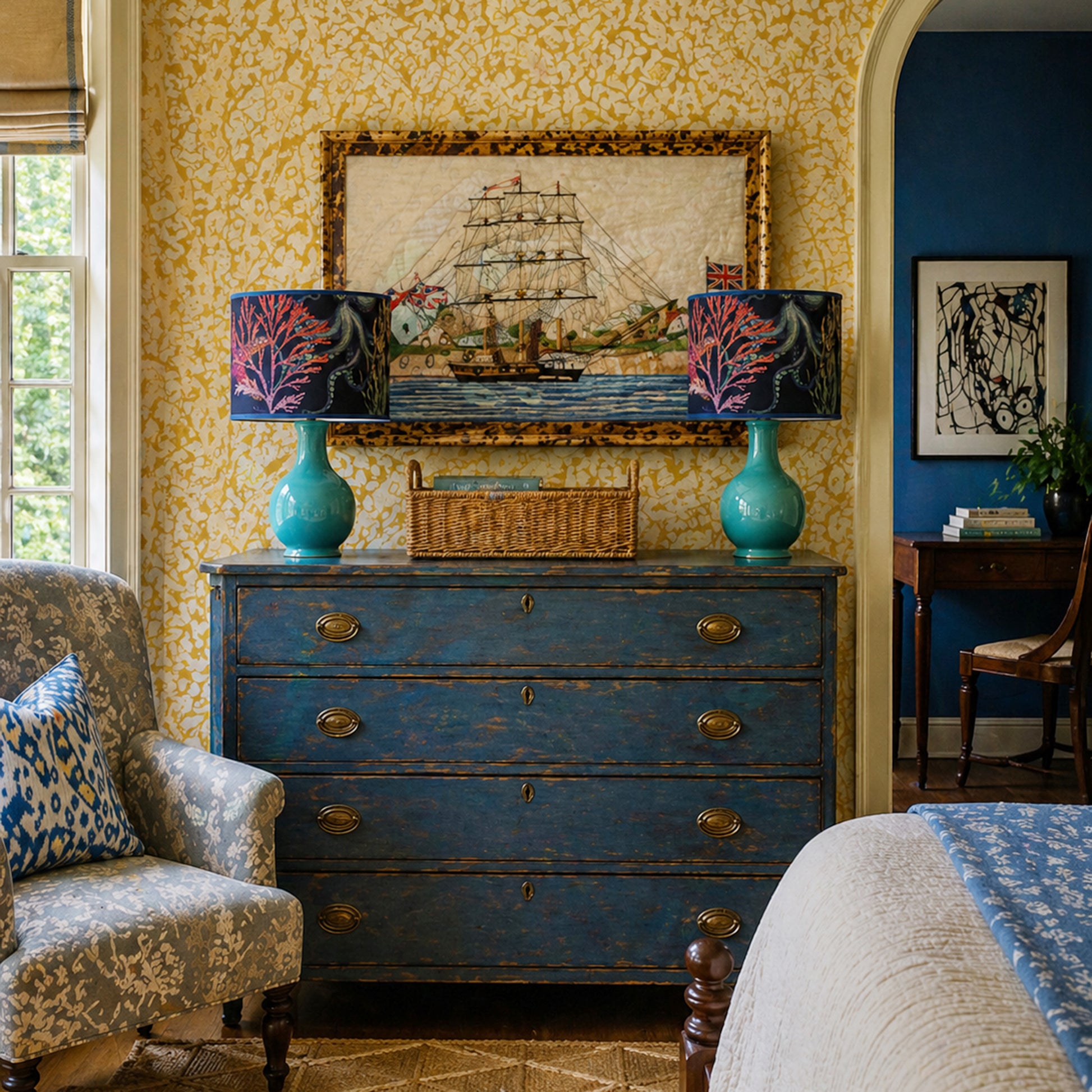 Living room with blue dresser, patterned lamps, and ship painting on yellow wall.