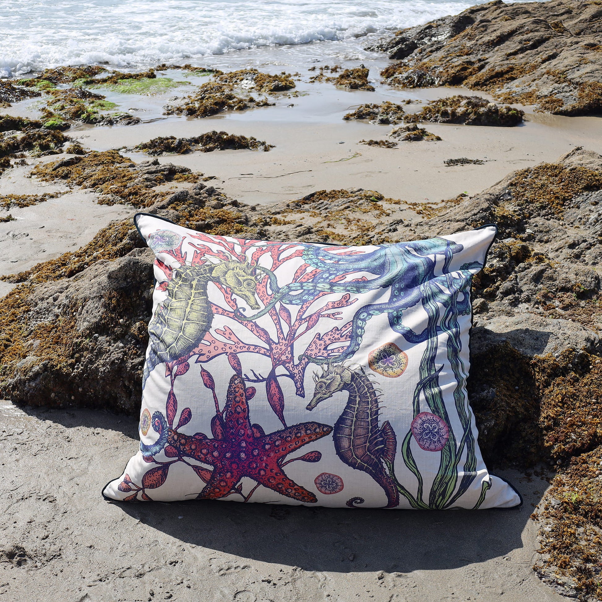 Decorative pillow with a marine pattern on a rocky beach