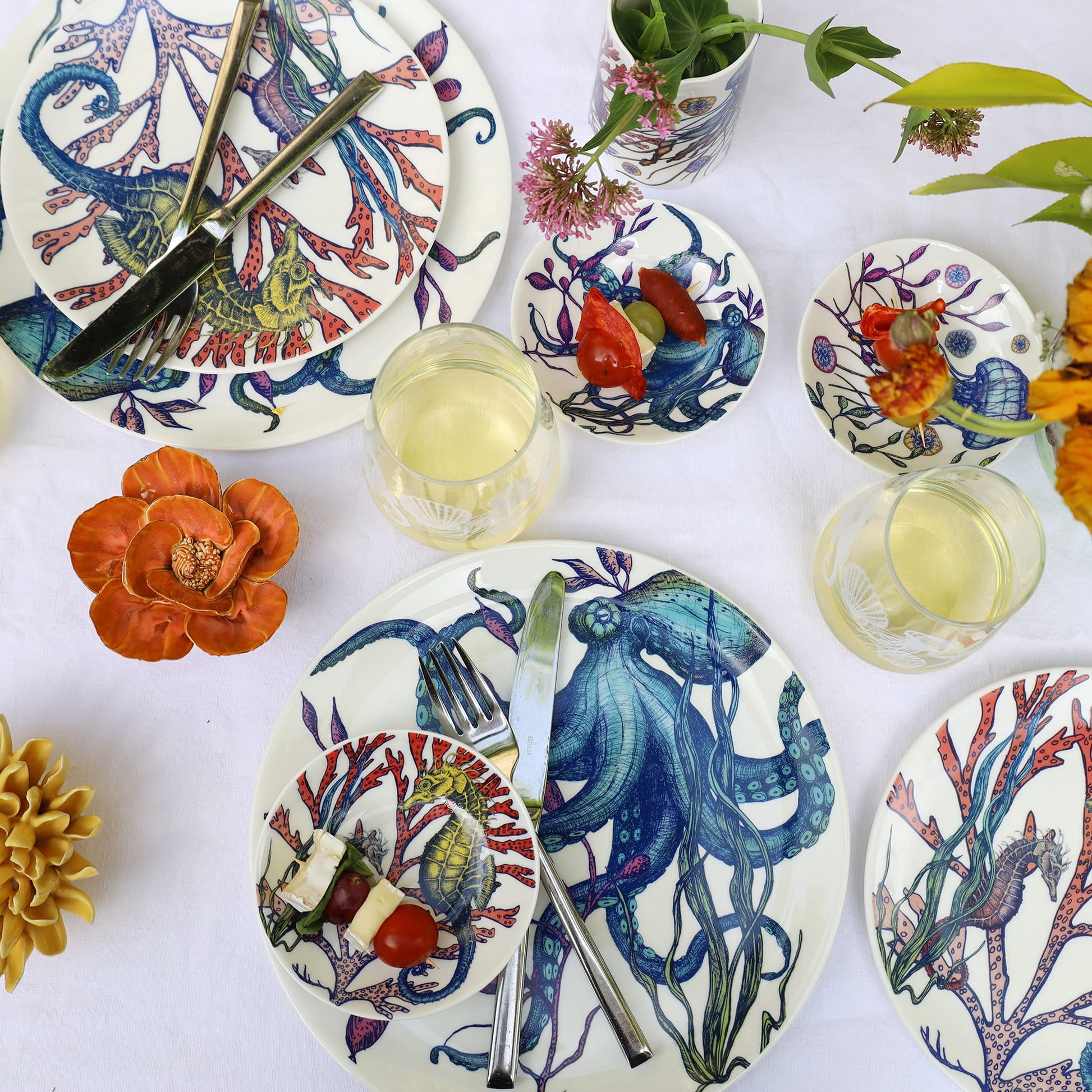 Colorful table setting with decorative plates featuring marine life designs on a white surface.
