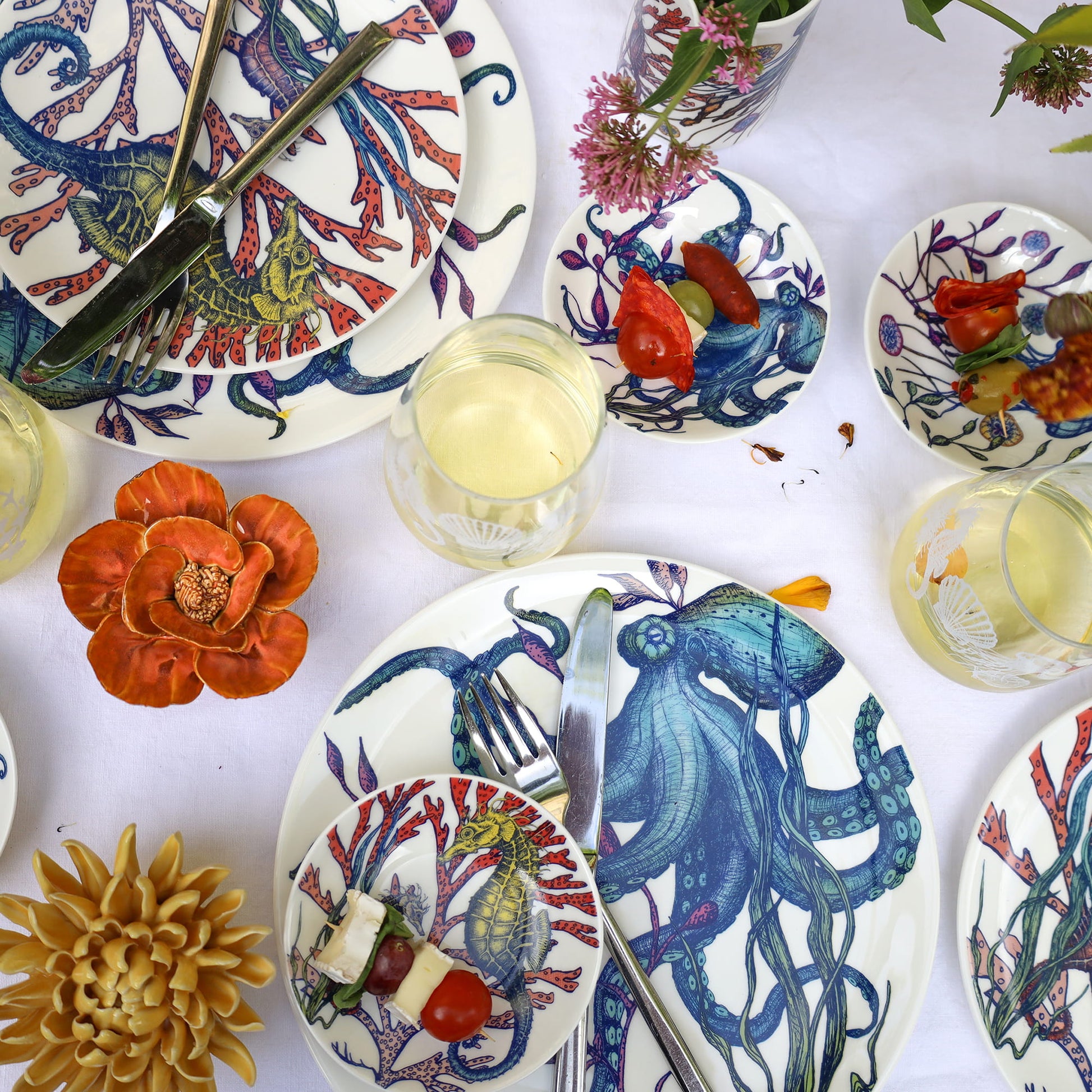 Colorful ceramic plates with underwater-themed designs on a white tablecloth.