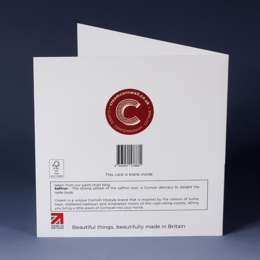 back of white greeting card with barcode, description and red cream cornwall logo standing on an ombre blue background