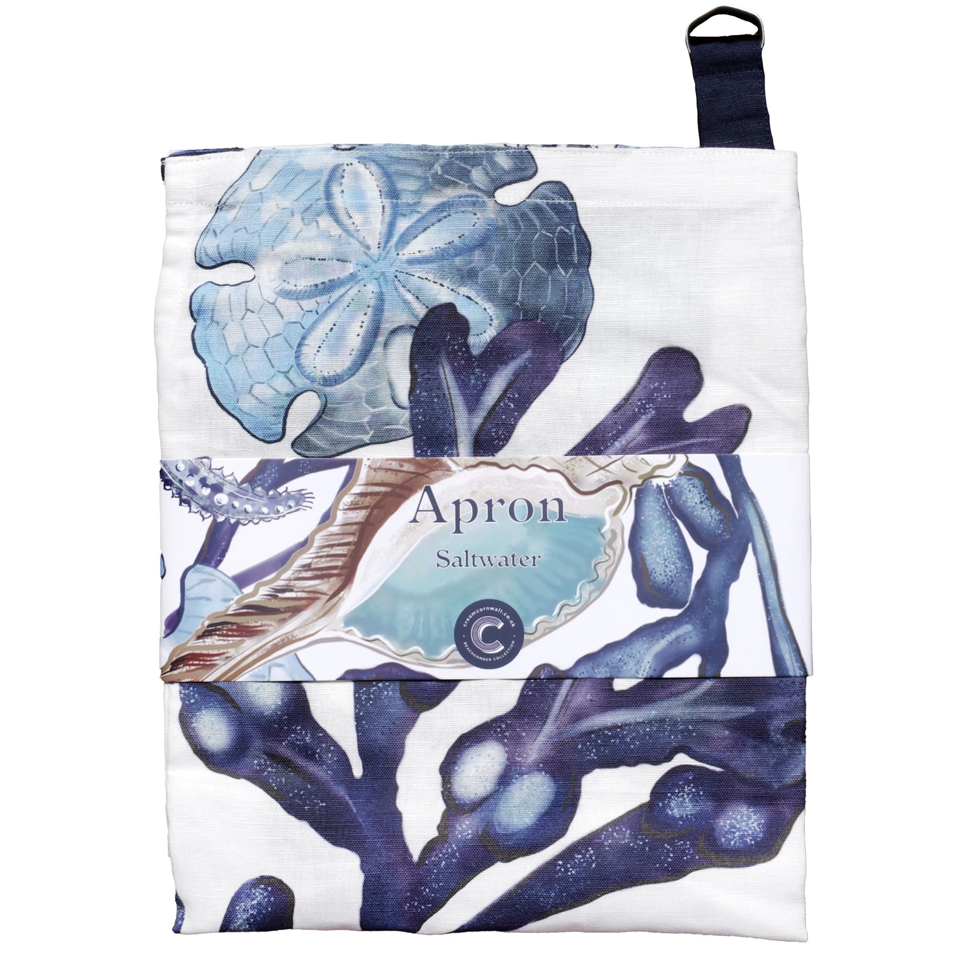 Folded apron with a coastal-themed design featuring illustrations of seaweed, a sand dollar, and seashells in shades of blue and white. The apron is wrapped with a branded label that reads 'Apron – Saltwater,' highlighting the marine-inspired artwork.