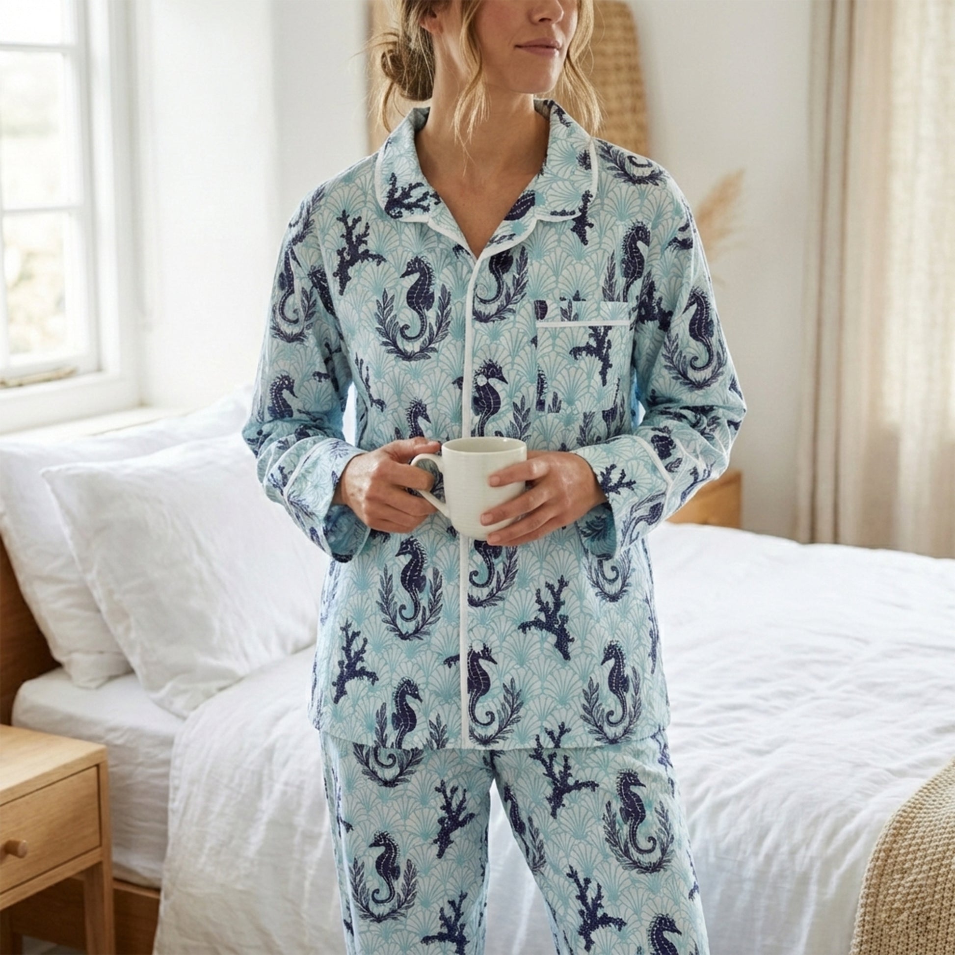 Person wearing a blue pyjama set with seahorse pattern in a bedroom.