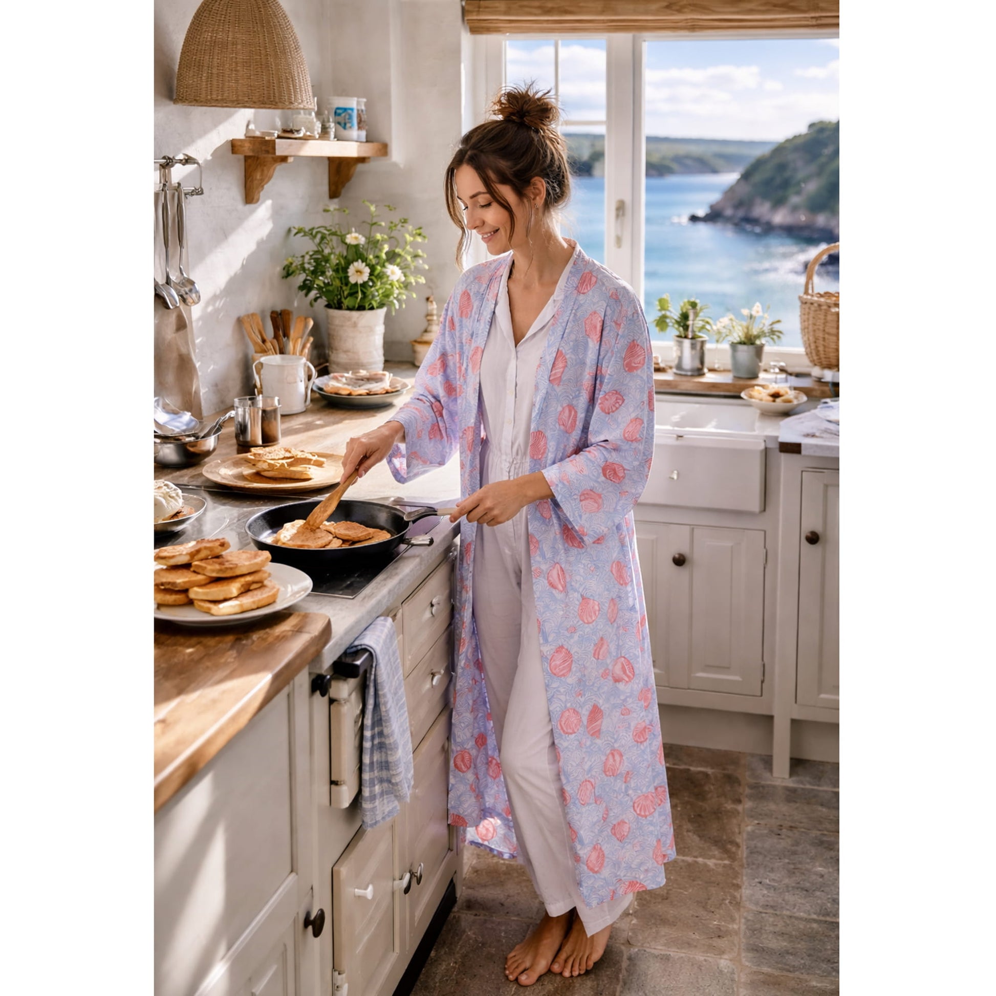 Woman in a patterned robe cooking in a kitchen with a scenic view.