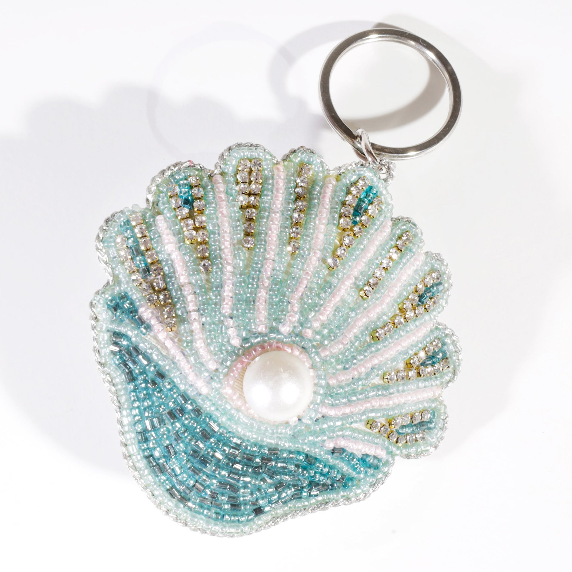 A beaded shell keyring decorated with turquoise, pink, and gold beads and a central pearl detail, displayed against a white background.